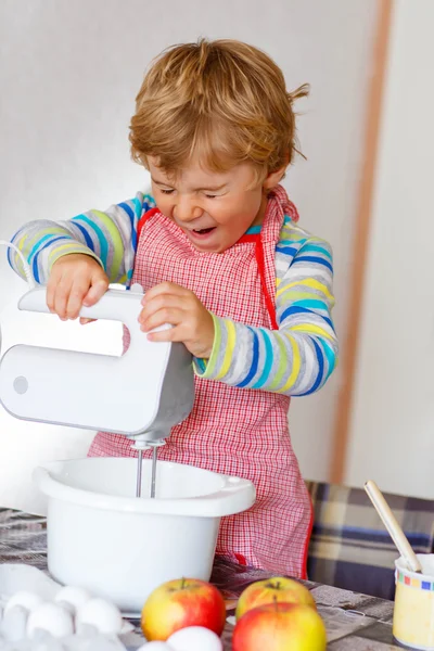 Vicces szőke gyerek fiú sütés almás sütemény beltéri — Stock Fotó