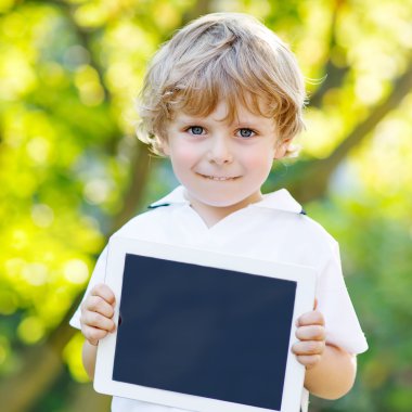 Preschool little boy with tablet pc, outdoors