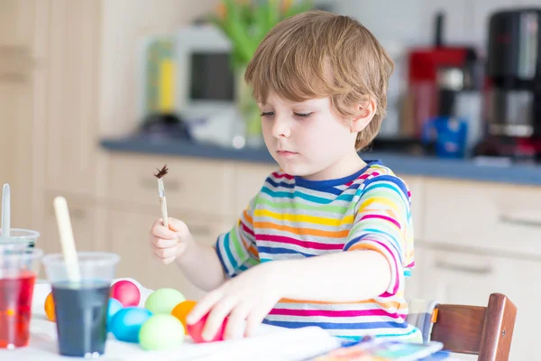 Маленький хлопчик розмальовує яйця на великоднє свято — стокове фото