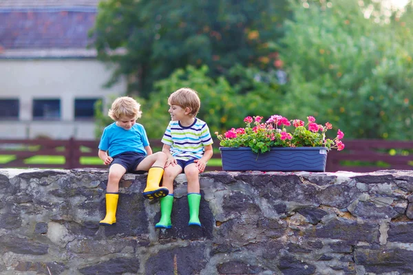 Two little kid boys sitting together on stone bridge — Zdjęcie stockowe