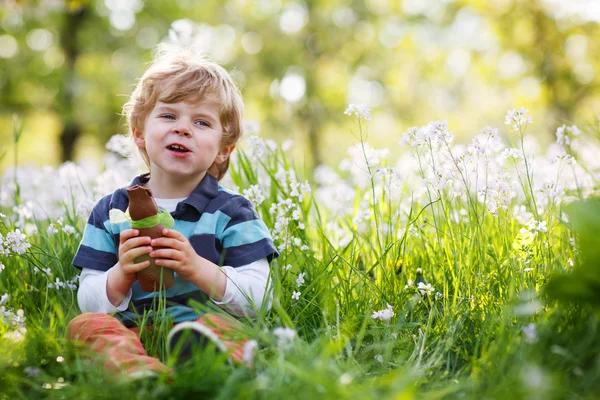 Lindo niño feliz comiendo conejito de chocolate en vacaciones de Pascua —  Fotos de Stock