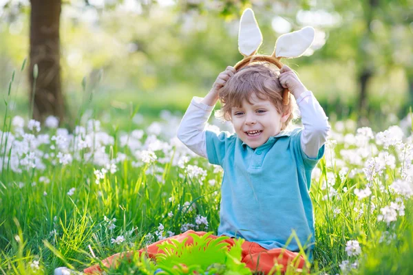 Симпатичный счастливый мальчик в пасхальных ушах кролика на весенне-зеленом — стоковое фото