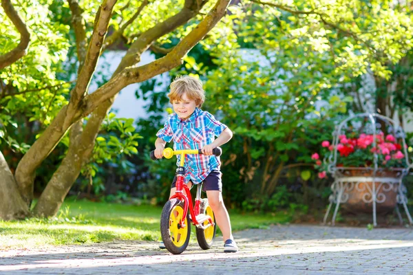 Chłopiec dziecko jazdy trójkołowy lub rowerów w ogrodzie — Zdjęcie stockowe