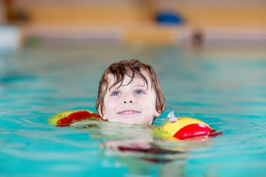 küçük çocuk çocuk swimmies bir kapalı havuzda yüzmek için öğrenme ile