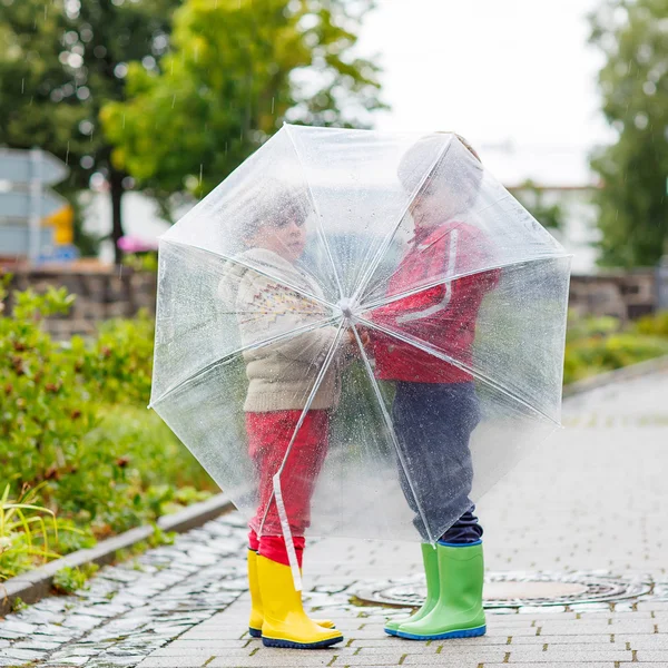 Two little kid boys with big umbrella outdoors — Stockfoto