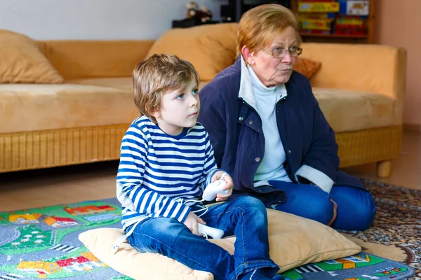 Kleine jongen jongen en grootmoeder spelen video game console — Stockfoto