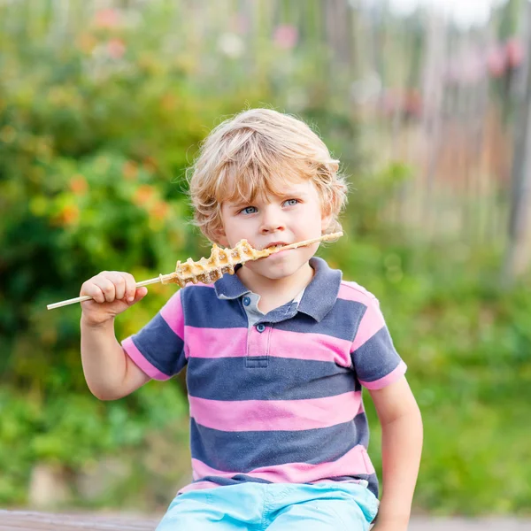 Bonito menino loiro comendo waffle na palha — Fotografia de Stock