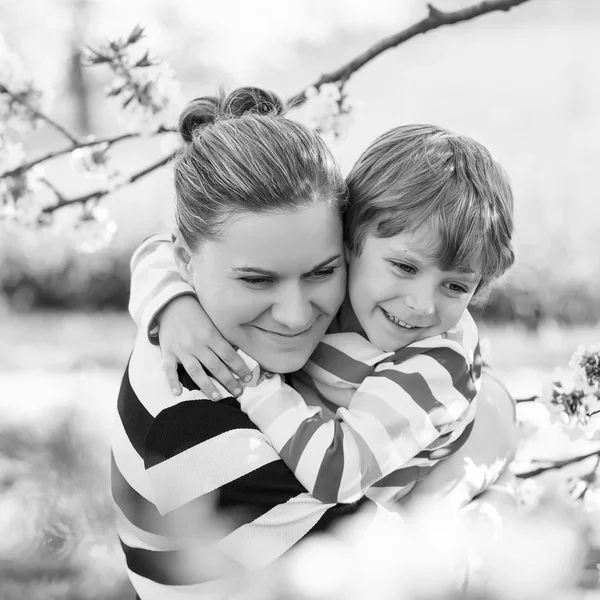 若い母親と小さな子供男の子咲く庭で楽しんで — ストック写真