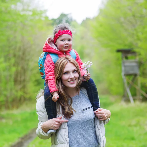 Vacker mor bär liten flicka på axlar. — Stockfoto