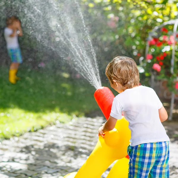 Twee kleine kinderen spelen met tuinslang in de zomer — Stockfoto