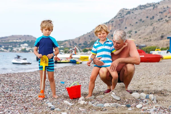 Dědeček a dva malé dítě chlapce na ocean beach — Stock fotografie