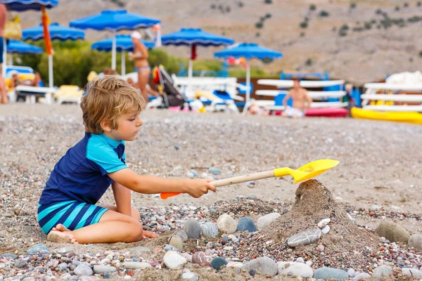 Little kid boy playing on beach with stones — Stock Photo, Image