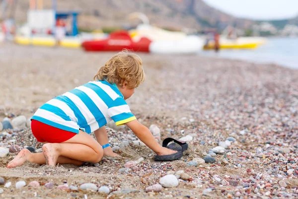 Menino brincando na praia com pedras — Fotografia de Stock