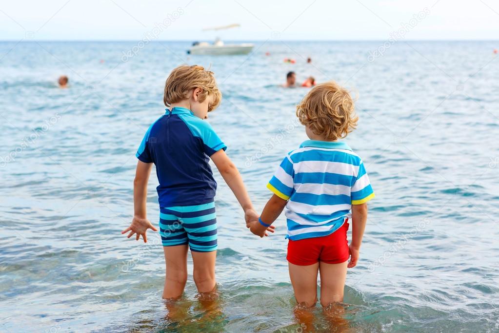 Two little kid boys taking bath in ocean