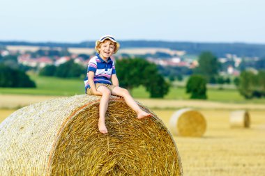 Yaz aylarında saman balya üzerinde oturan küçük çocuk çocuk