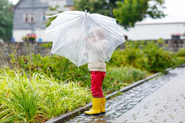 Liten blond liten pojke promenader med stora paraply utomhus — Stockfoto