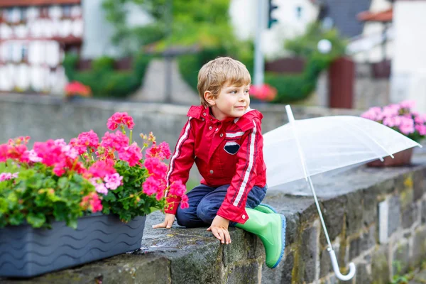Little blond kid boy with big umbrella outdoors — Stockfoto