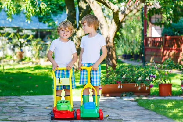 Dois meninos brincando com brinquedos de cortador de grama — Fotografia de Stock