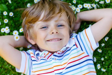 Cute kid boy laying on green grass in summer