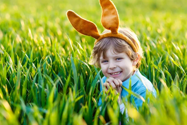Adorable niño con orejas de conejo de Pascua jugando en gras verde — Foto de Stock