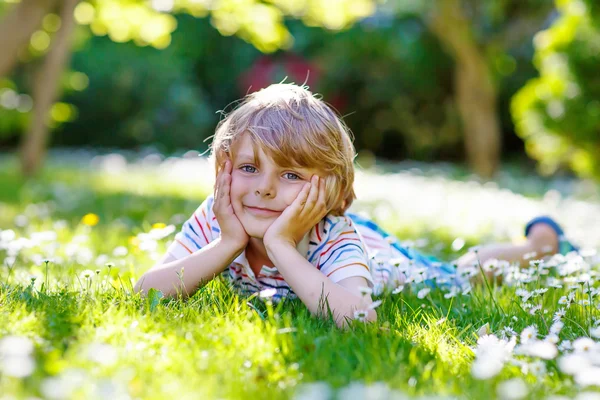 Gelukkig kind jongen opleggen van groen gras in de zomer — Stockfoto