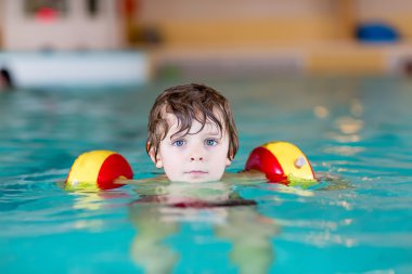 küçük çocuk çocuk swimmies bir kapalı havuzda yüzmek için öğrenme ile