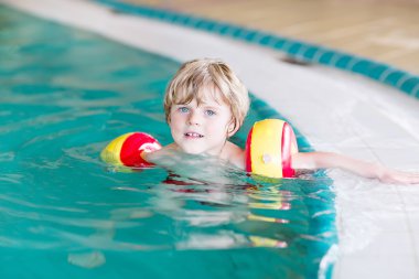 küçük çocuk çocuk swimmies bir kapalı havuzda yüzmek için öğrenme ile