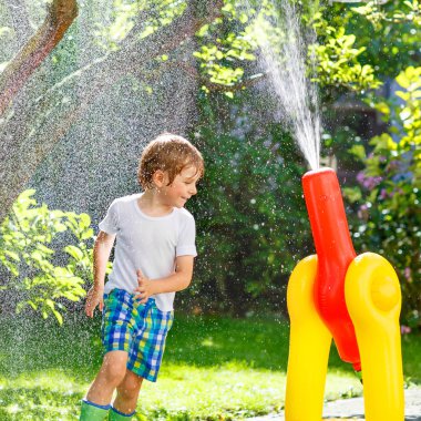 bir bahçe ile oynarken küçük çocuk çocuk hortum ve su