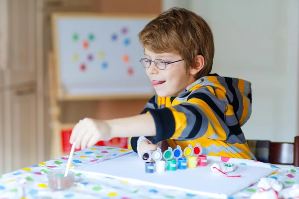 Маленький мальчик рисует с красочными акварелями в помещении — стоковое фото