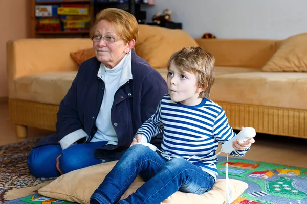 Kleine jongen jongen en grootmoeder spelen video game console — Stockfoto