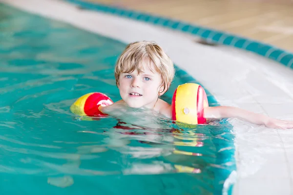 Bambino con il costume da bagno che impara a nuotare in una piscina coperta — Foto Stock