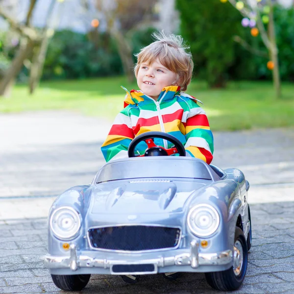 Piccolo bambino in età prescolare guida grande giocattolo vecchia auto d'epoca, all'aperto — Foto Stock