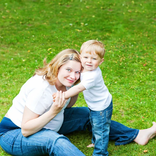 Pregnant woman and adorable little toddler son in garden.