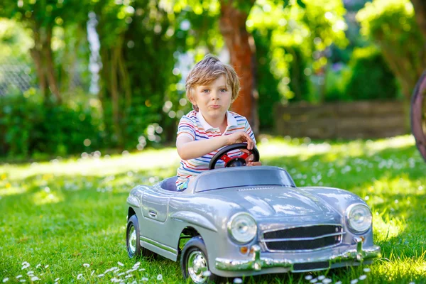 Niño conduciendo con un gran coche de juguete al aire libre — Foto de Stock