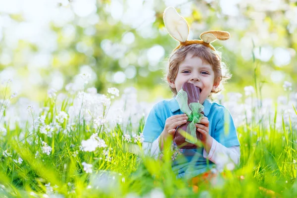 Malé dítě chlapec jíst čokoládové Velikonoční zajíček venku — Stock fotografie