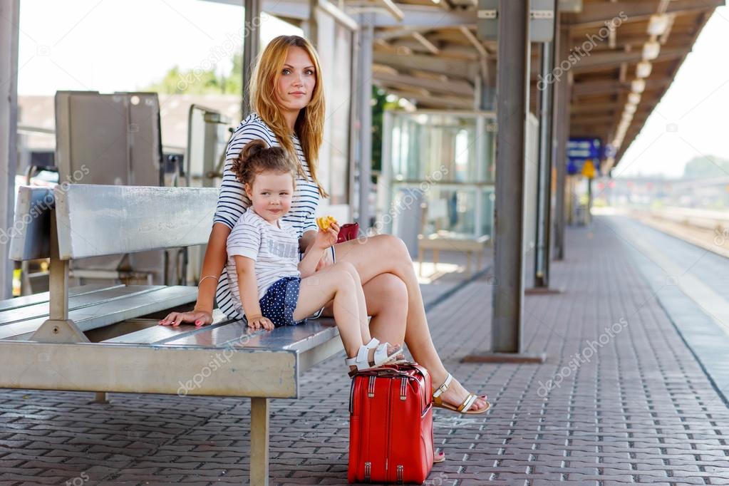 Cute little girl and mother on a railway station.