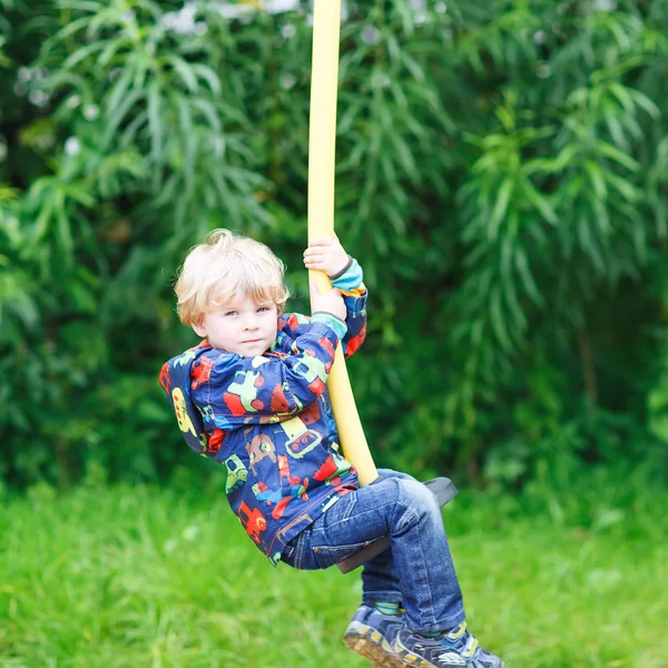 Pequeno menino sorridente de três anos se divertindo no balanço — Fotografia de Stock