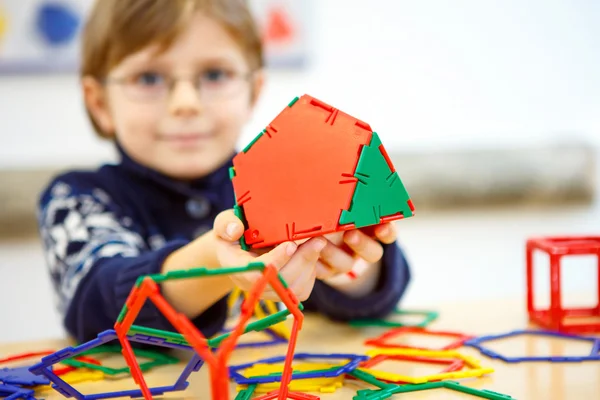 Kleiner Junge baut geometrische Figuren aus Plastikklötzen — Stockfoto