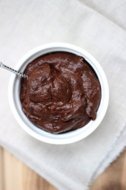 Vegan avokado çikolata mousse (puding) bir kase içinde gümüş kaşıkla. Dikey yönlendirme, yukarıda görünümünden.