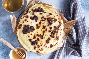 Bir yığın ev yapımı çıtır ekmek, bal ve bitki çayı, mavi beton arka plan..