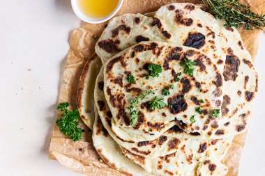 Indian homemade traditional flatbread with fresh parsley and olive oil. Chapati, roti or naan Indian crispy flatbread. clipart