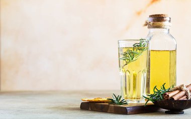 Uzun bardakta elma şarabı ve biberiye, tarçın ve kurutulmuş meyve cipsi, açık beton arka plan. Seçici odak.