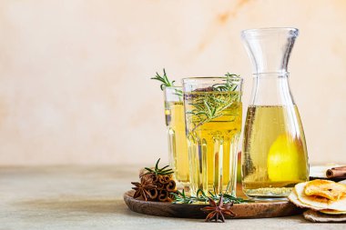 Bardakta armut ya da elma şarabı ve biberiye, tarçın ve taze organik armutla birlikte şişe. Mayalanmış meyve suyu. Hafif beton arka plan. Seçici odak.