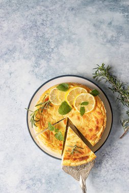 Biberiye, nane ve limon dilimleri ile süslenmiş limonlu peynirli kek. Ricotta peynirli kek ya da güveç yok. Mavi arka plan. Üst görünüm.