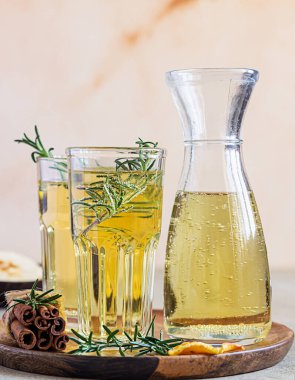 Bardakta armut ya da elma şarabı ve biberiye, tarçın ve taze organik armutla birlikte şişe. Mayalanmış meyve suyu. Hafif beton arka plan. Seçici odak.