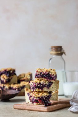 Ev yapımı böğürtlen reçeli, kısa kenarlı kareler ve bir bardak süt, açık beton arka plan. Seçici odak.