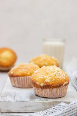 Vanilyalı kek ve kağıt bardaklarda streusel ve hafif arka planda bir bardak süt. Çocuklar için kahvaltı ya da atıştırmalık.