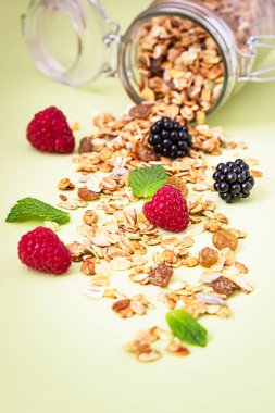 Yeşil arka planda müsli ya da ahududu, böğürtlen ve nane aromalı müsli ya da granola karışımı. Sağlıklı gıda konsepti.