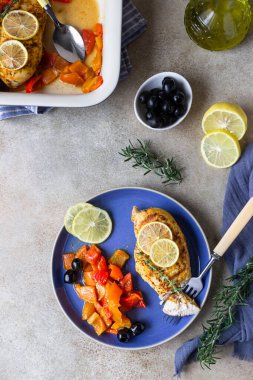 Fırında pişirilmiş veya ızgara tavuk göğsü fırında dolmalık biber, limon ve zeytin, açık beton arka plan. Sağlıklı yiyecekler. Üst görünüm.