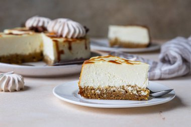 Beyaz seramik tabakta tuzlu karamelli ve kremalı havuçlu vanilyalı cheesecake, açık beton zemin. Seçici odak.